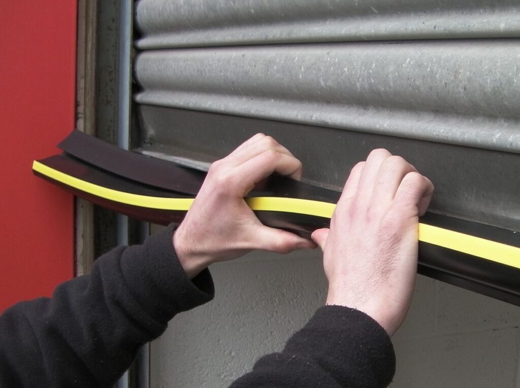 Garage door technician is performing maintenance repairs on a commercial garage door