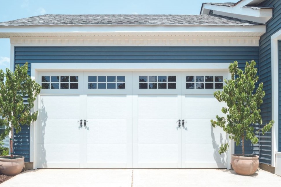 A two-car garage door, featuring white, carriage house style doors by Wayne Dalton.