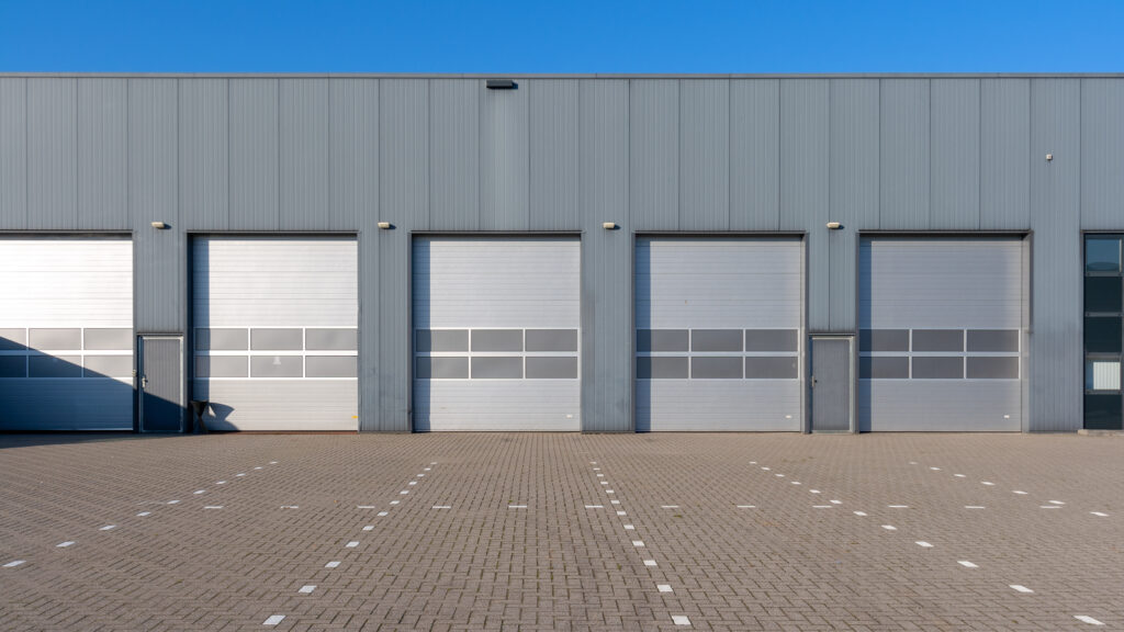 Row of grey industrial units with roller shutter doors.